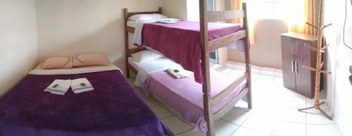Pousada Zacarias في أورو بريتو: سريرين بطابقين في غرفة مع ملاءات أرجوانية