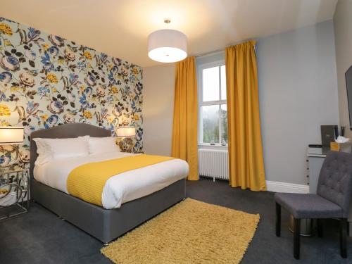 a bedroom with a bed and a chair and a window at Cartmel Old Grammar in Cartmel