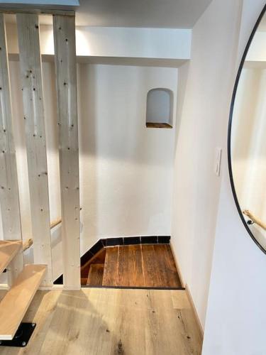Cette chambre dispose de murs blancs, d'un miroir et de parquet. dans l'établissement Maison Alsacienne & Moderne en Hypercentre, à Colmar