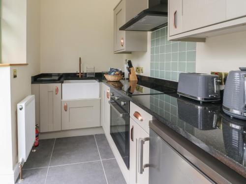 a kitchen with white cabinets and black counter tops at The Stables in Denbigh