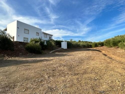 a white building on the side of a dirt road at Casa Caraza. Un olivar con vistas al castillo de Juego de Tronos in Almodóvar del Río