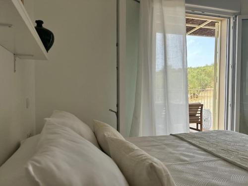 a white bedroom with a bed with a window at Casa Caraza. Un olivar con vistas al castillo de Juego de Tronos in Almodóvar del Río