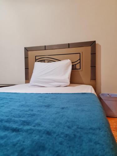 1 cama con manta azul y almohada blanca en Happy vista pyramids inn en El Cairo