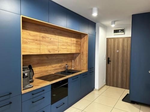 a kitchen with blue cabinets and a sink at Apartament Klifowy Raj SPA & Restaurant by Stayly in Niechorze