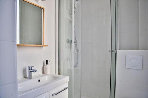 uma casa de banho branca com um chuveiro e um lavatório. em Jeux Olympiques 2024, Stade de France em Saint-Denis