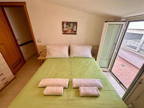 a bedroom with a green bed with two towels on it at Sperlonga Paradise Apartment Complex in Sperlonga