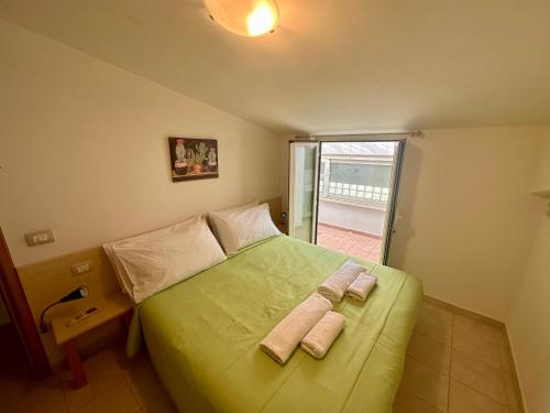 a bedroom with a green bed with two towels on it at Sperlonga Paradise Apartment Complex in Sperlonga
