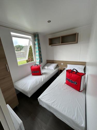 萊馬特的住宿－Mobil'home - Camping **** Les Charmettes，两个红色的袋子坐在房间里两张床上