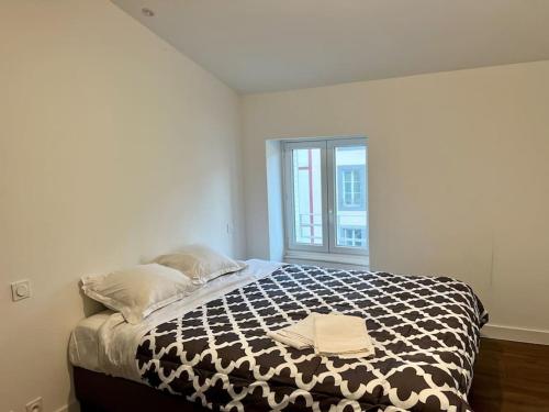 um quarto com uma cama com um edredão preto e branco em Magnifique Appartement CL-FD Centre Historique Marché Poissons em Clermont-Ferrand