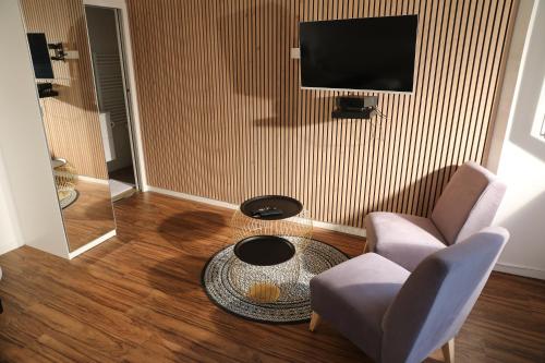 ein Wohnzimmer mit einem TV, einem Stuhl und einem Tisch in der Unterkunft Eiffel Tour Cosy chesterfield in Paris