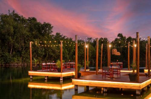 a dock with tables and chairs on the water at night at Fairmont Mayakoba in Playa del Carmen