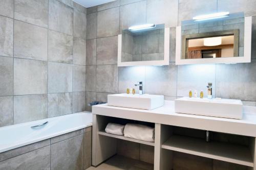 een badkamer met 2 wastafels en een bad bij Résidence Carre Blanc - 2 Pièces pour 2 Personnes 084 in Courchevel