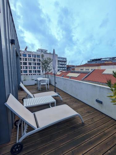 a balcony with chairs and an umbrella on a building at 54 São Paulo - Exclusive Apartment Hotel in Lisbon