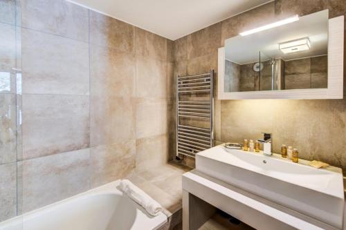 bagno con vasca, lavandino e specchio di Résidence Carre Blanc - 4 Pièces pour 6 Personnes 394 a Courchevel