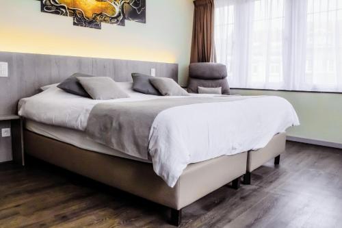 una camera da letto con un grande letto con lenzuola bianche di Hotel des Postes a Houffalize