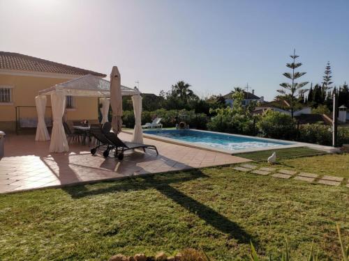 un patio trasero con una piscina con mesa y sillas en Suite Huelva garden, en Aljaraque
