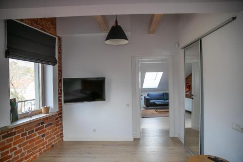a living room with a brick wall and a tv at Charming Apartment in Kaunas Old Town with Balcony in Kaunas