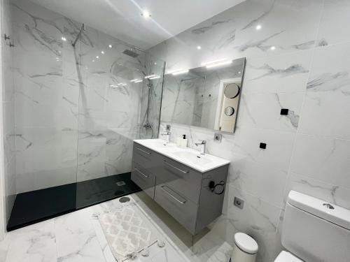 Baño blanco con lavabo y espejo en Jandia Beach Apartment 2, en Morro del Jable