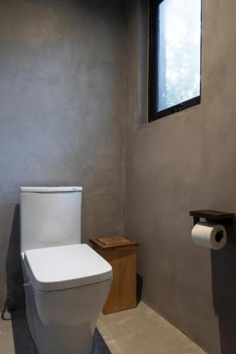 a bathroom with a white toilet and a window at UMi Tulum in Tulum
