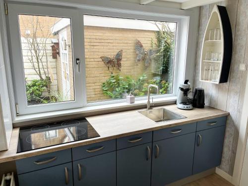 a kitchen with a sink and a large window at Pollux bij Vuurtoren en strand in Noordwijk aan Zee