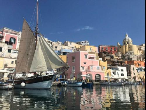 a sail boat in the water in front of buildings at Palazzo Palumbo in Procida