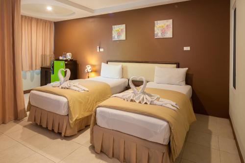 two beds in a hotel room with towels on them at The Right Resort in Pattaya