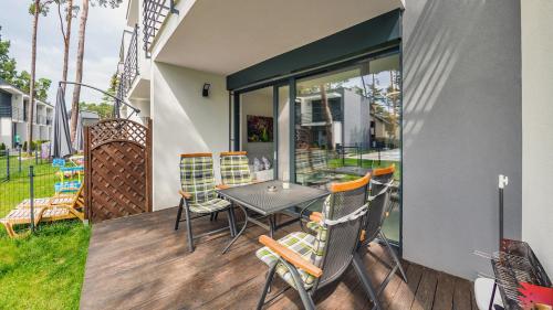 a patio with a table and chairs on a deck at Prestige House Apartament - 2 sypialnie z ogródkiem i basenem in Pobierowo