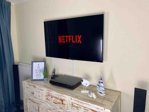 une télévision sur un mur avec un ordinateur portable sur une commode dans l'établissement discovAIR Graal Müritz -Haus Quisisana- Strandnah mit Netflix, à Graal-Müritz