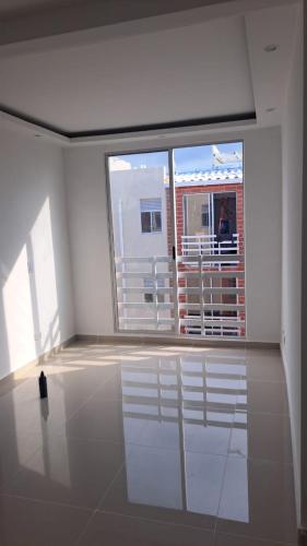 Apartamento في بارانكويلا: غرفة بيضاء مع نافذة كبيرة وشخص على شرفة