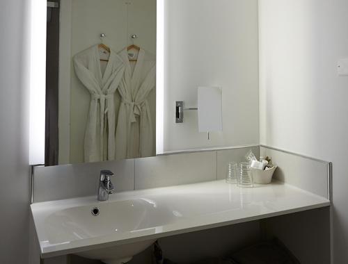 a white bathroom with a sink and a mirror at The Originals Hôtel Le Cise Restaurant Chambres et Suites in Ault