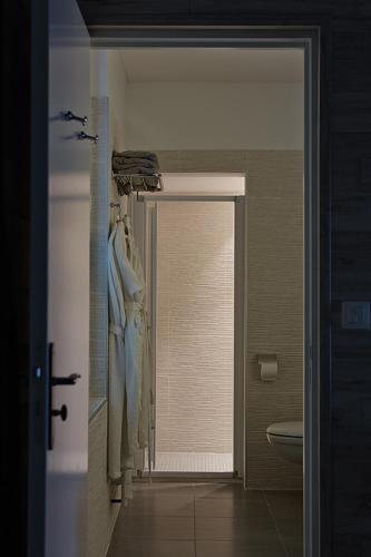 a bathroom with a door leading to a toilet and a sink at The Originals Hôtel Le Cise Restaurant Chambres et Suites in Ault