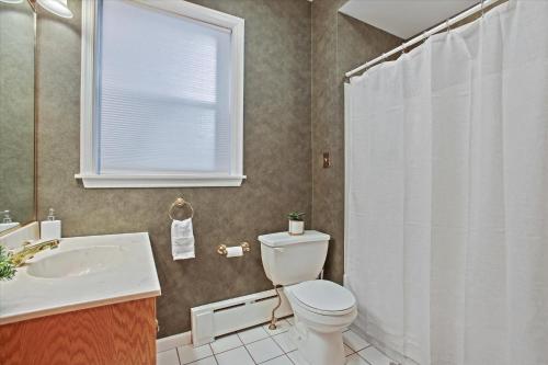 a bathroom with a toilet and a sink and a window at Greenridge Getaway:Near Universities & Attractions in Scranton