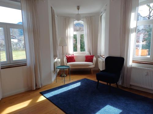 sala de estar con alfombra azul, silla y ventana en Landhaus Haser, en Oberammergau