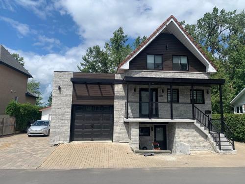 a house with a garage with a car parked in front at Impeccable, modern, river view, renovated cottage in Laval