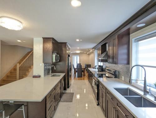a large kitchen with wooden cabinets and a staircase at Impeccable, modern, river view, renovated cottage in Laval