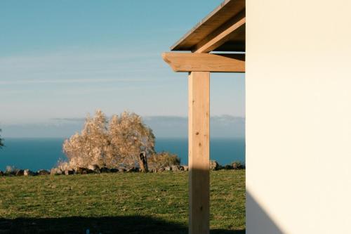 a wooden cross in a field with the ocean in the background at NEW SUITES SEA VIEW SARDINIA, Bedda Ista in Castelsardo
