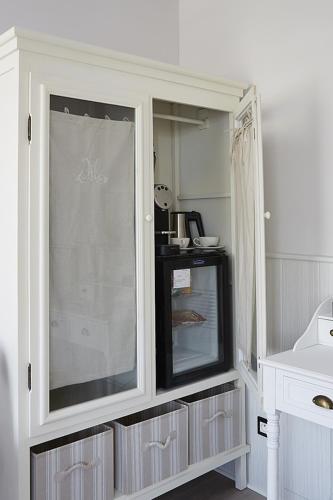 a white cabinet with a glass door in a kitchen at The Originals Hôtel Le Cise Restaurant Chambres et Suites in Ault