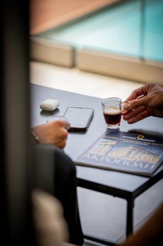 a person sitting at a table with a drink and a glass at 4RosesVillas in Litochoro