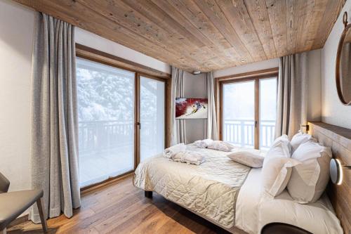 a bedroom with a bed and a large window at Résidence Bois Du Ban - Chalets pour 10 Personnes 764 in le Praz