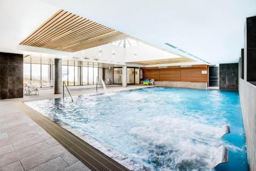 duży basen z niebieską wodą w budynku w obiekcie Résidence Les Flocons Du Soleil - Chalets pour 6 Personnes 474 w mieście Germ