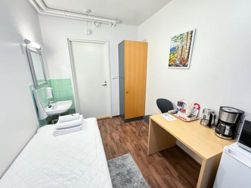 a small room with a desk and a sink at Hostelli Matkustajakoti in Kuopio