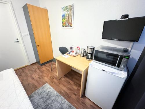 a small room with a desk and a microwave at Hostelli Matkustajakoti in Kuopio