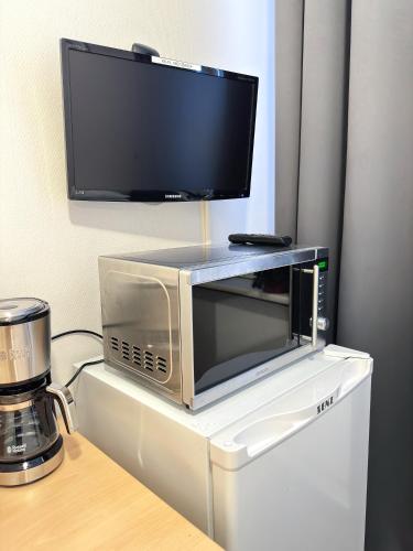 a microwave with a tv on top of a refrigerator at Hostelli Matkustajakoti in Kuopio