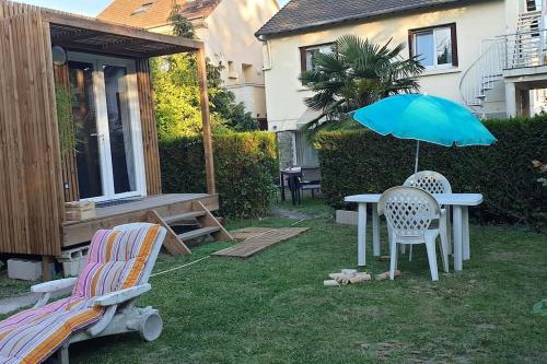 una mesa y dos sillas y una sombrilla en un patio en studio GK15 GREENAPPART+ jardin SQY, Versailles.., en La Verrière