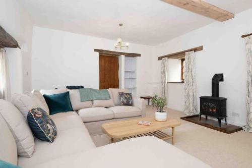 a living room with a white couch and a wood stove at Spacious country retreat in the heart of Devon. in Crediton