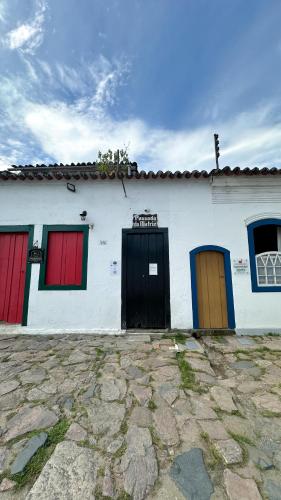 a white building with red and blue doors on it at Pousada Matriz in Paraty
