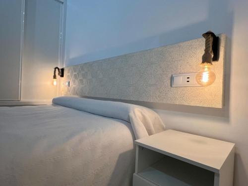 Dormitorio blanco con cama y interruptor de luz en SANTA CLARA Con opción a Parking, en Jaén