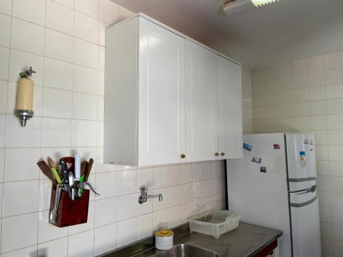 a kitchen with white cabinets and a refrigerator at Praia de Geribá C 4 in Búzios
