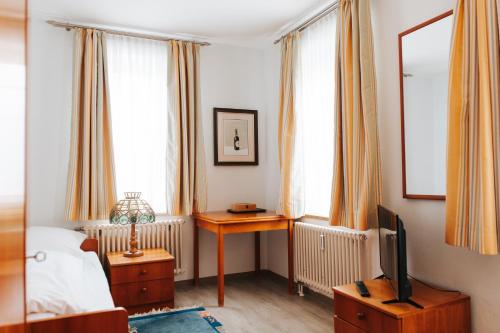 a bedroom with a bed and a desk with a tv at Unertl Bräustüberl Gästehaus in Haag in Oberbayern