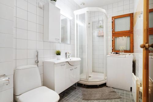a white bathroom with a toilet and a sink at Villa Kataja in Rovaniemi